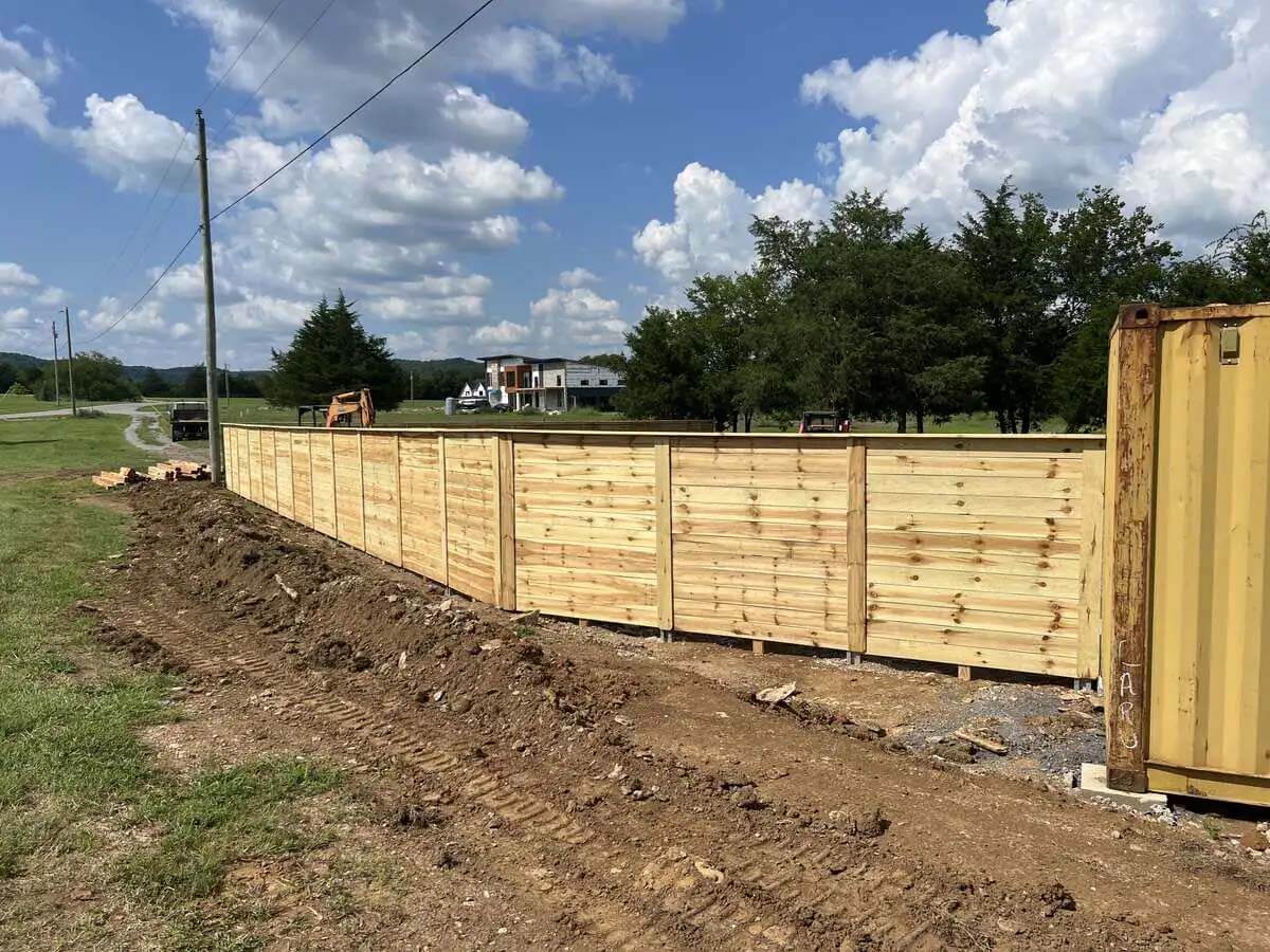 Horizontal privacy wood fence with tabletop design installed around the side of a property line