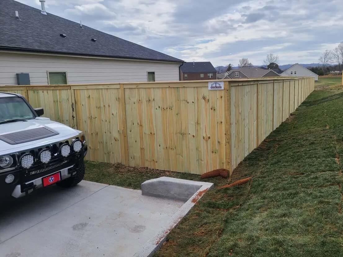 Stockade wood fence with cap and trim design installed around a residential backyard
